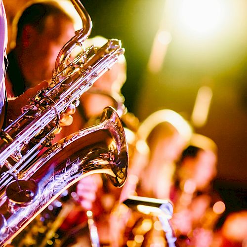 A group of musicians playing saxophones under bright stage lights, creating a lively and vibrant atmosphere.