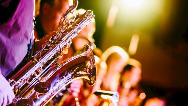 A group of musicians playing saxophones under bright stage lights, creating a lively and vibrant atmosphere.