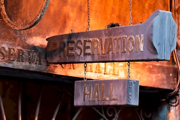 The image shows a weathered sign reading "Preservation Hall" on a rustic exterior, suggesting a historic or cultural venue.