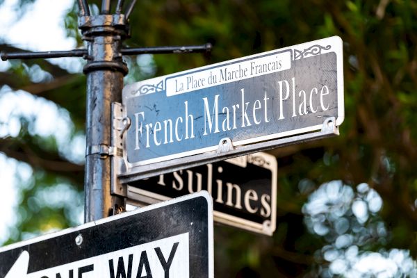 The image shows street signs for French Market Place and Ursulines, along with a one-way sign.